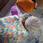 Handmade crochet cushion and colorful yarn balls.