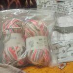 Yarn balls in packaging on patterned fabric background.