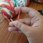 Hand holding colorful yarn with blurred background.