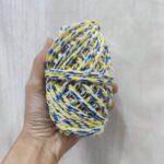 Hand holding colorful twisted yarn bundle.