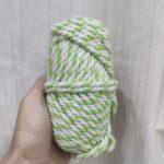 Green and white yarn skein held in hand.