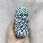 Hand holding blue and white twisted rope.