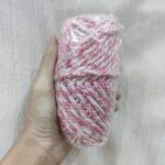 Hand holding pink and white yarn skein.