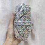 Hand holding colorful skein of yarn.