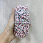 Hand holding multicolored baker's twine roll.