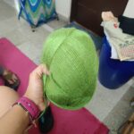 Person holding a green baseball cap indoors.