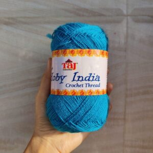 Hand holding blue crochet thread skein.